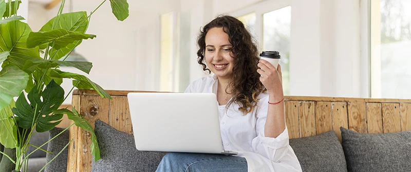 Persona comprando desde la computadora portátil con una taza de café en la mano